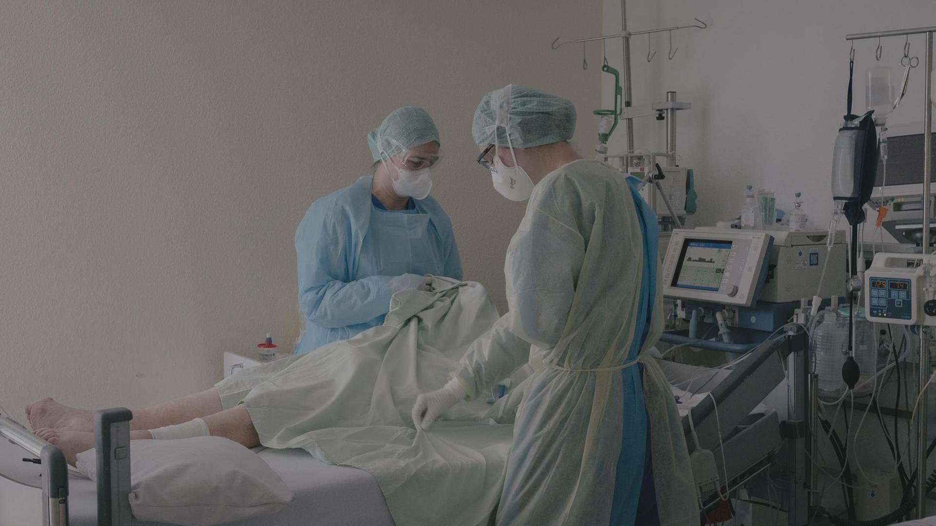 Krankenpflegerinnen am Bett eines COVID-19-Patienten auf der Intensivstation. Krankenpflegerinnen am Bett eines COVID-19-Patienten auf der Intensivstation.