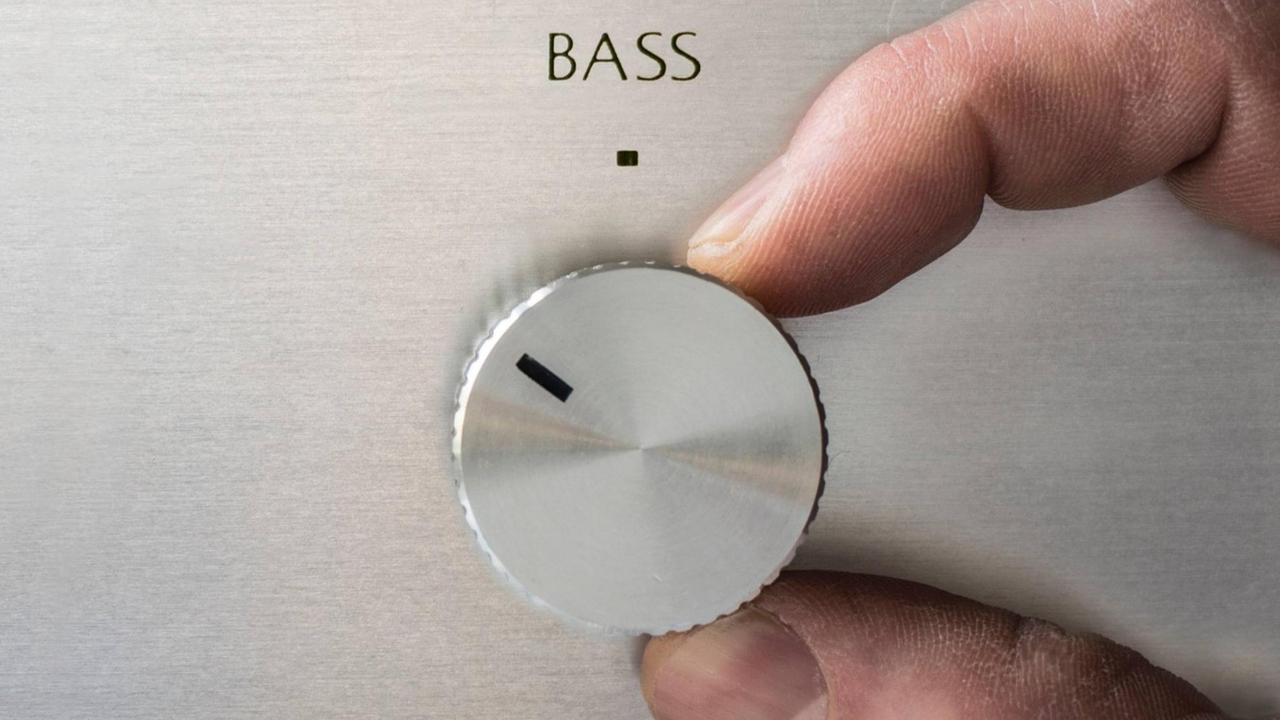 Eine Hand dreht am Bass-Regler einer Musikanlage Eine Hand dreht am Bass-Regler einer Musikanlage