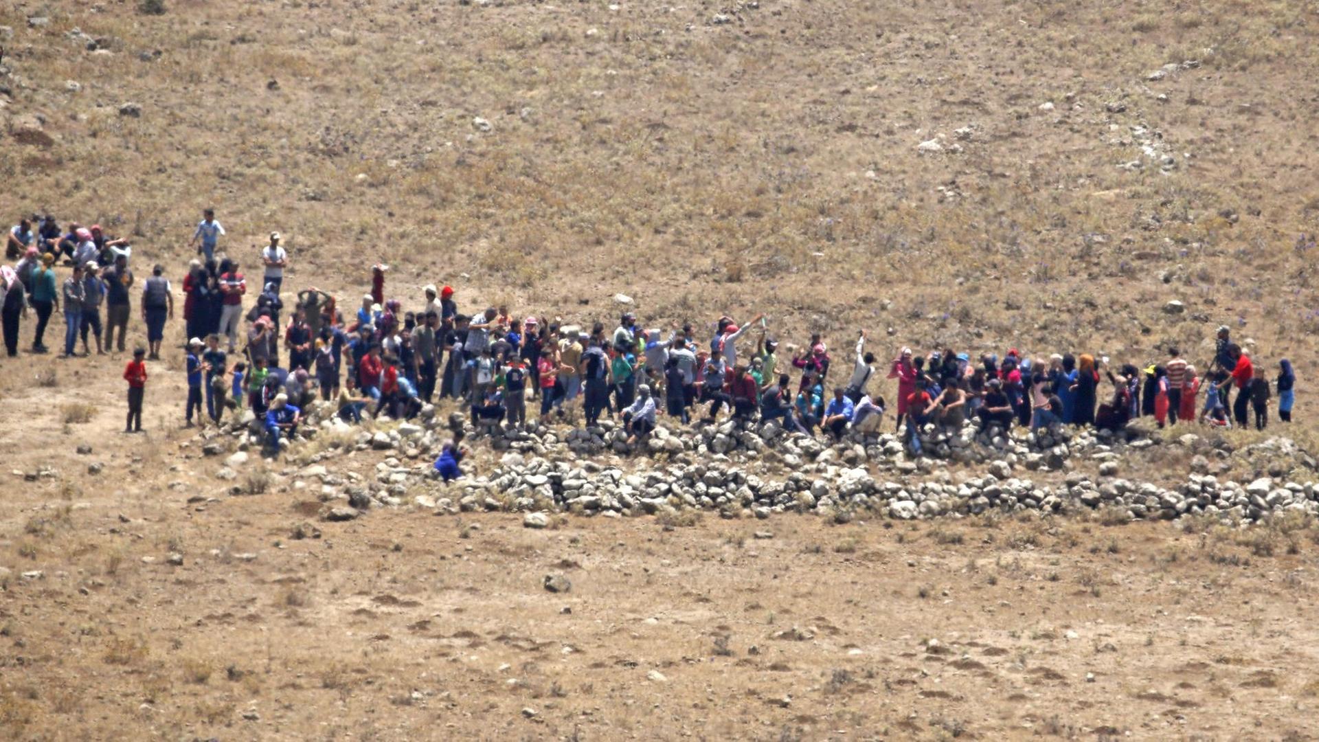 Zahlreiche Menschen in einer kargen Landschaft, aus der Ferne fotografiert. Zahlreiche Menschen in einer kargen Landschaft, aus der Ferne fotografiert.
