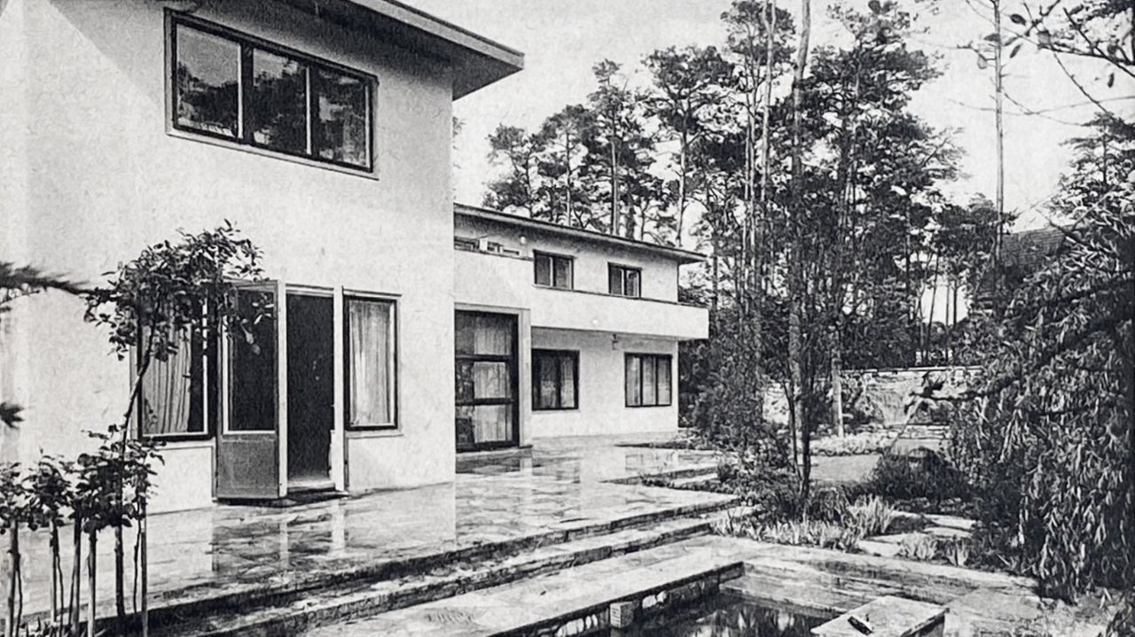 Ein schwarz-weiß Foto von zwei Flachbauten im Stil der neuen Sachlichkeit. Im Vordergrund ein Wasserbecken.