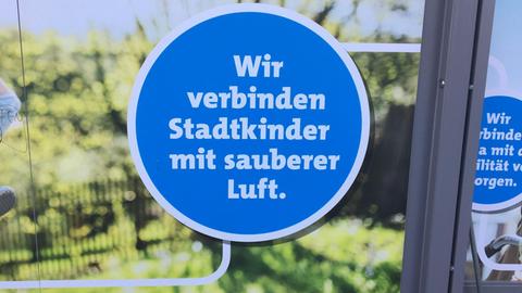 Werbung am Wiesbadener Hauptbahnhof. Auf einem Plakat steht: "Wir verbinden Stadtkinder mit sauberer Luft."