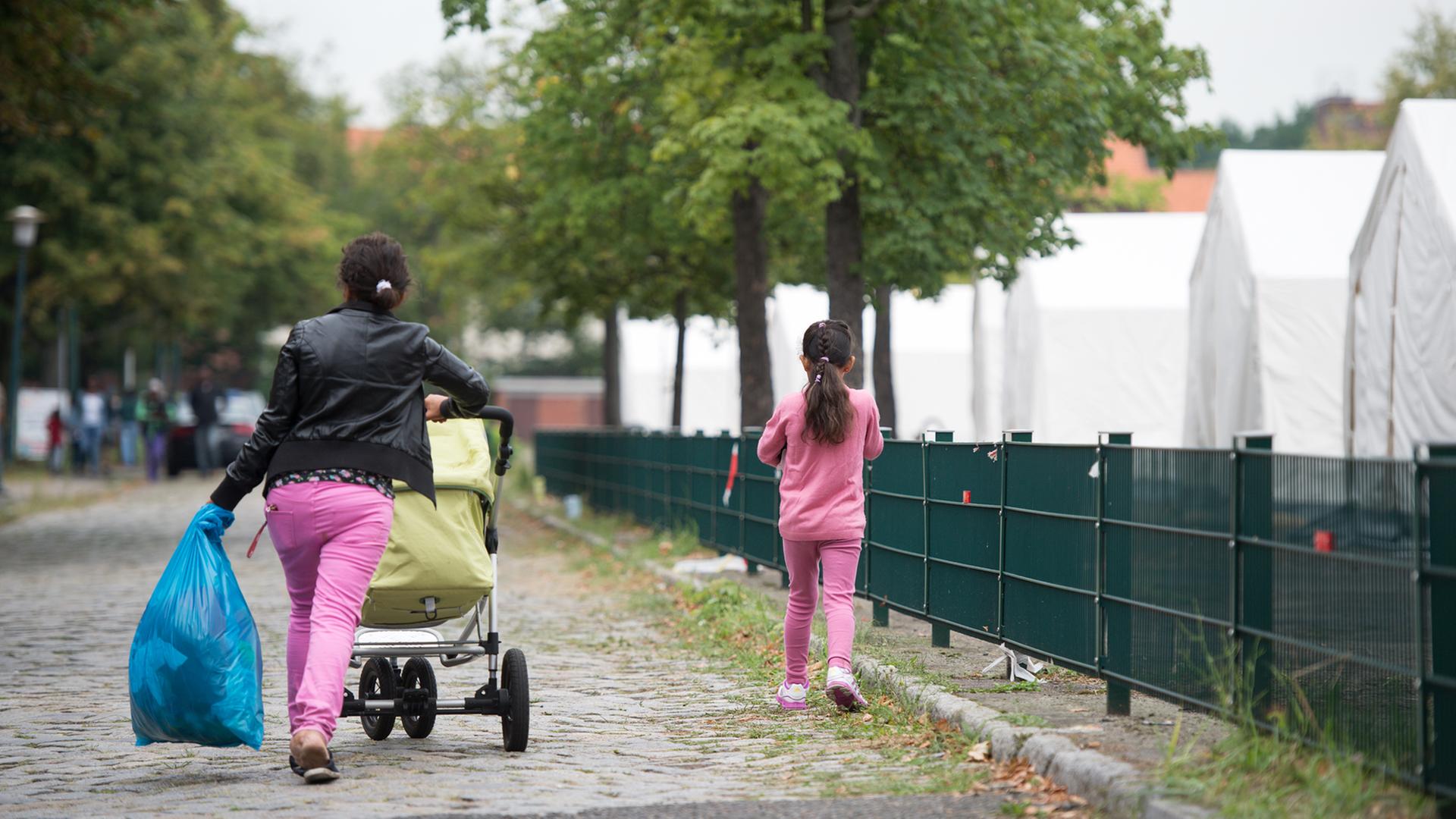 Flüchtlinge am Rand einer Zeltstadt auf einem ehemaligen Kasernengelände in Berlin Flüchtlinge am Rand einer Zeltstadt auf einem ehemaligen Kasernengelände in Berlin