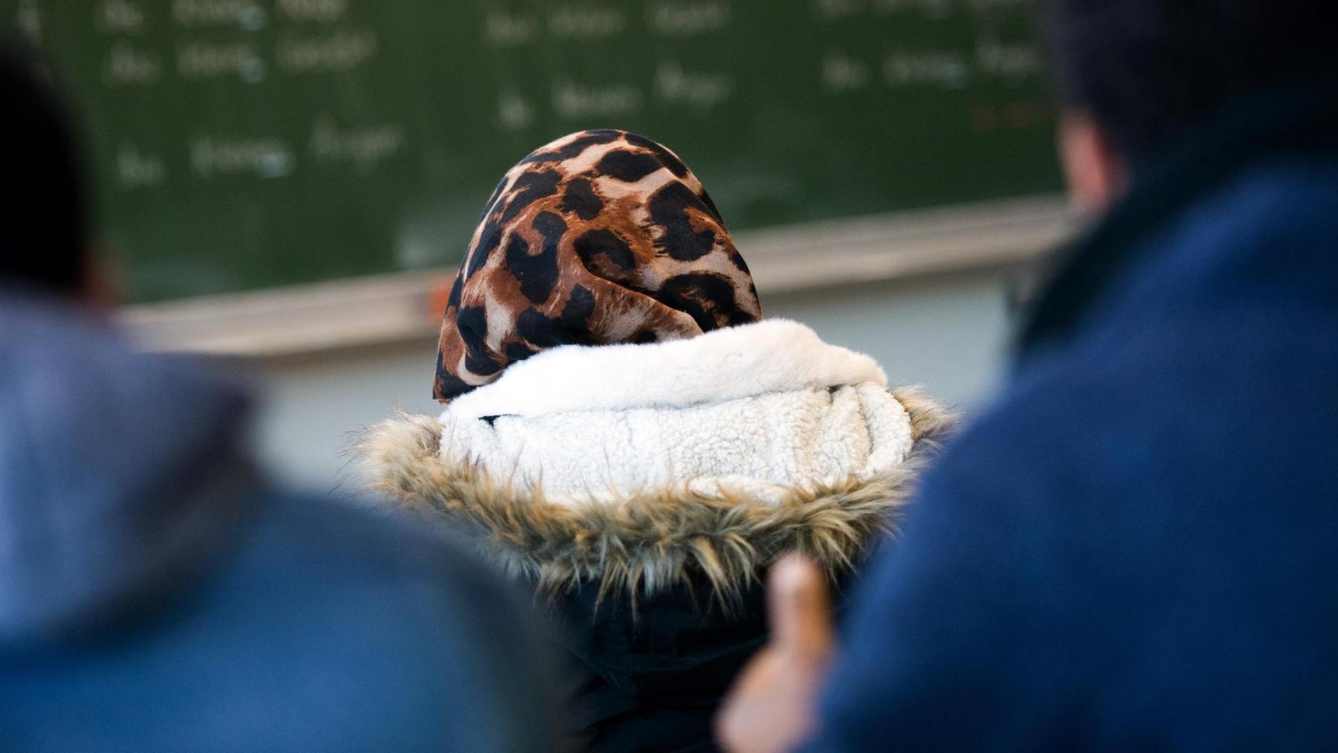 Eine Schülerin trägt im Klassenzimmer während des Unterrichtes eine Jacke und ein Kopftuch. Eine Schülerin trägt im Klassenzimmer während des Unterrichtes eine Jacke und ein Kopftuch.