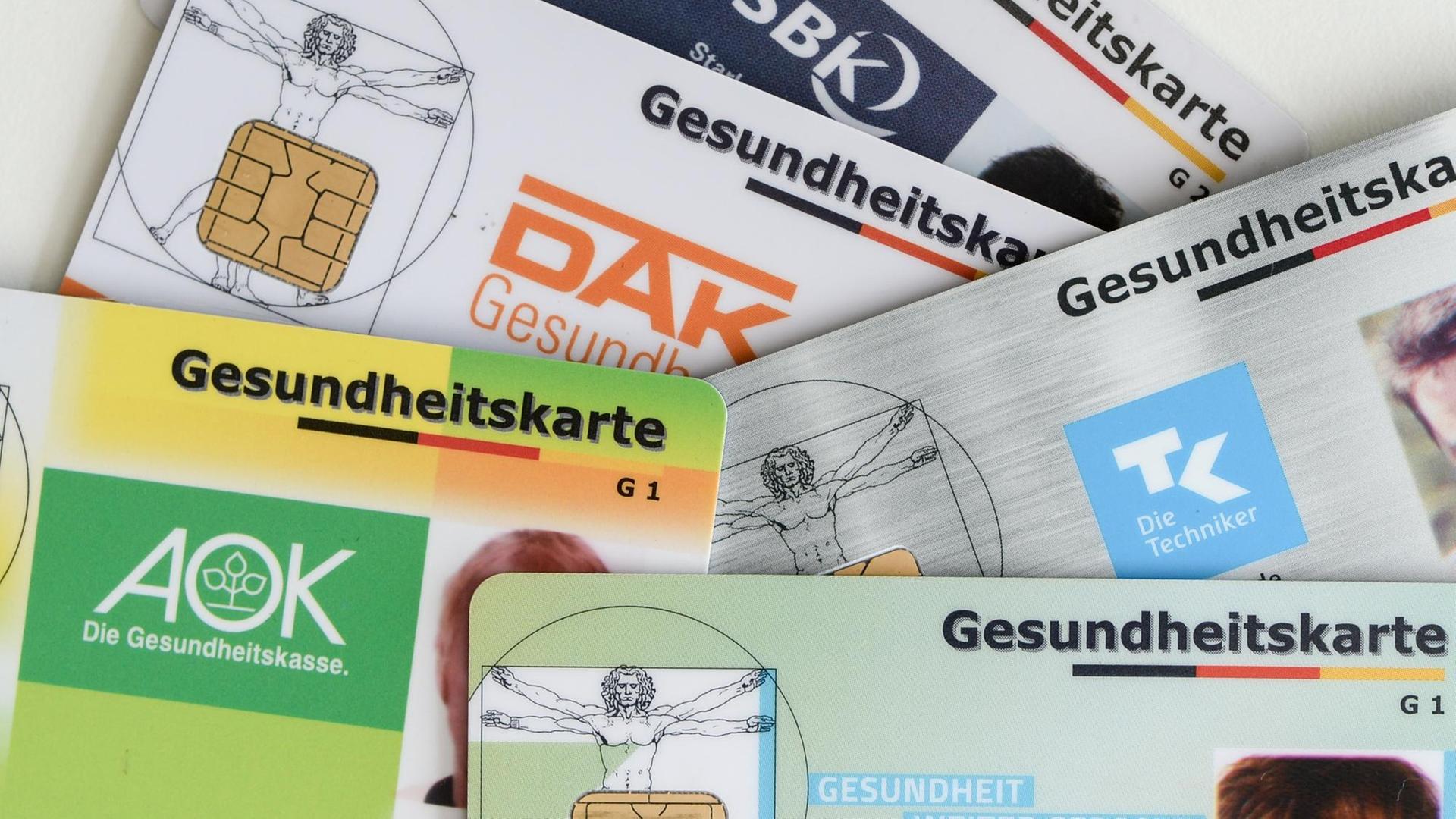 Gesundheitskarten verschiedener Krankenkassen liegen auf einem Tisch. Gesundheitskarten verschiedener Krankenkassen liegen auf einem Tisch.