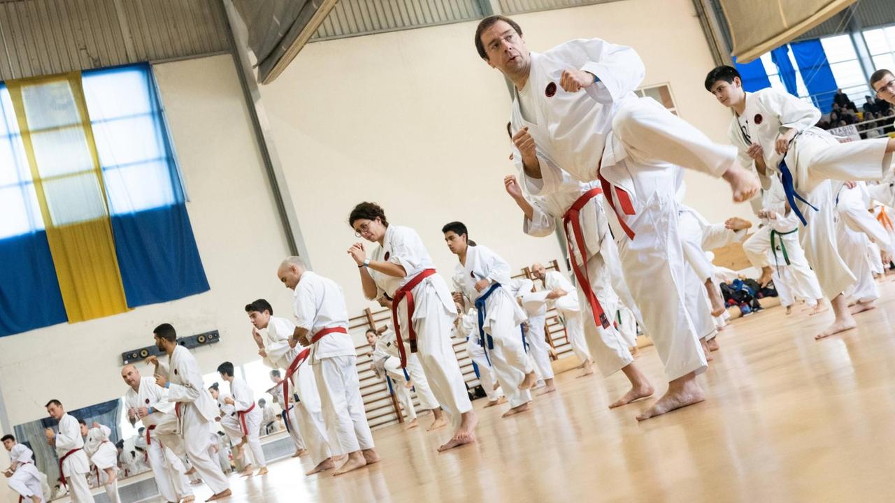 Ein Karate Event in Okinawa: In einer Turnhalle stehen dutzende Karatemeister in weißen Karateanzügen in Reihen. Ein Karate Event in Okinawa: In einer Turnhalle stehen dutzende Karatemeister in weißen Karateanzügen in Reihen.