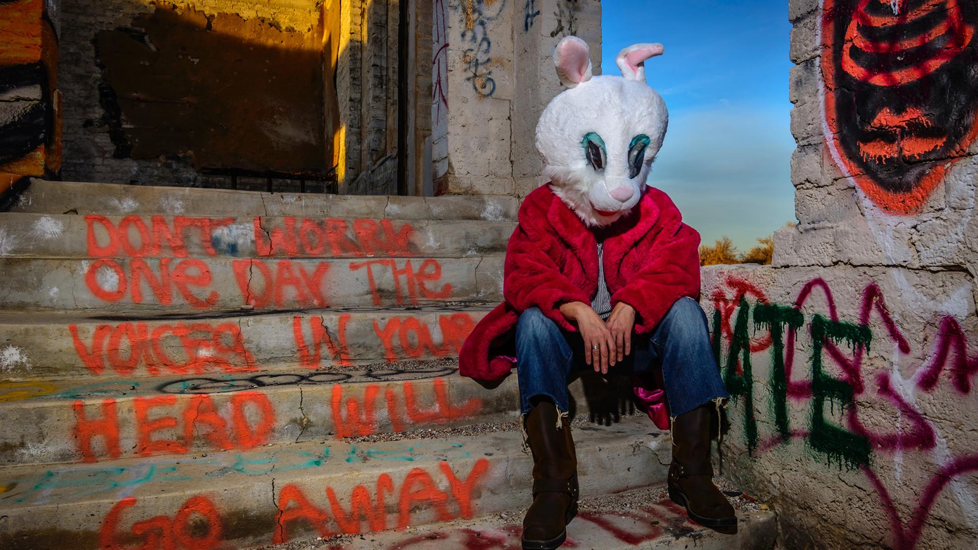 Ein Mann in einem Hasenkostüm sitzt auf einer Treppe mit Graffiti. Ein Mann in einem Hasenkostüm sitzt auf einer Treppe mit Graffiti.