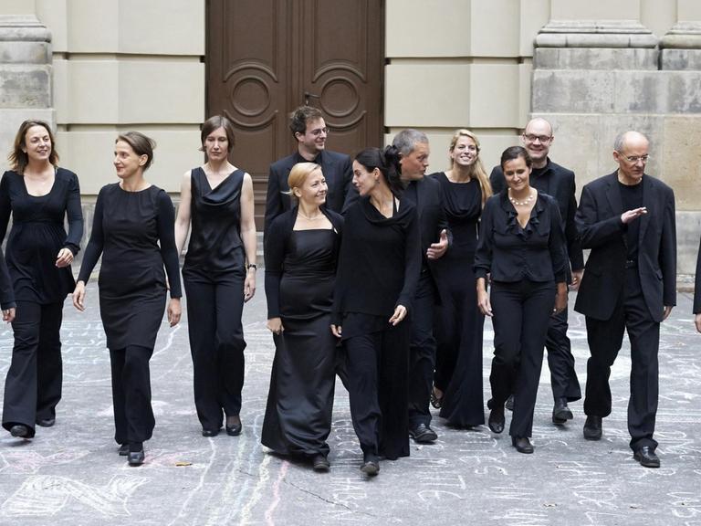 Das Vokalensemble Athesinus Consort Berlin in dunkler Kleidung vor einem Kirchenportal