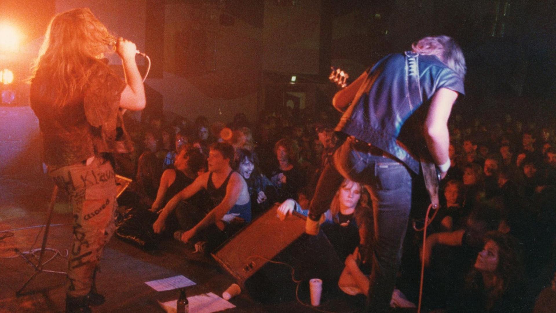 Man sieht die Band Darkland bei ihrem Auftritt im Berliner Langhansclub. Die Musiker haben lange Haare und spielen vor einem euphorischen Publikum