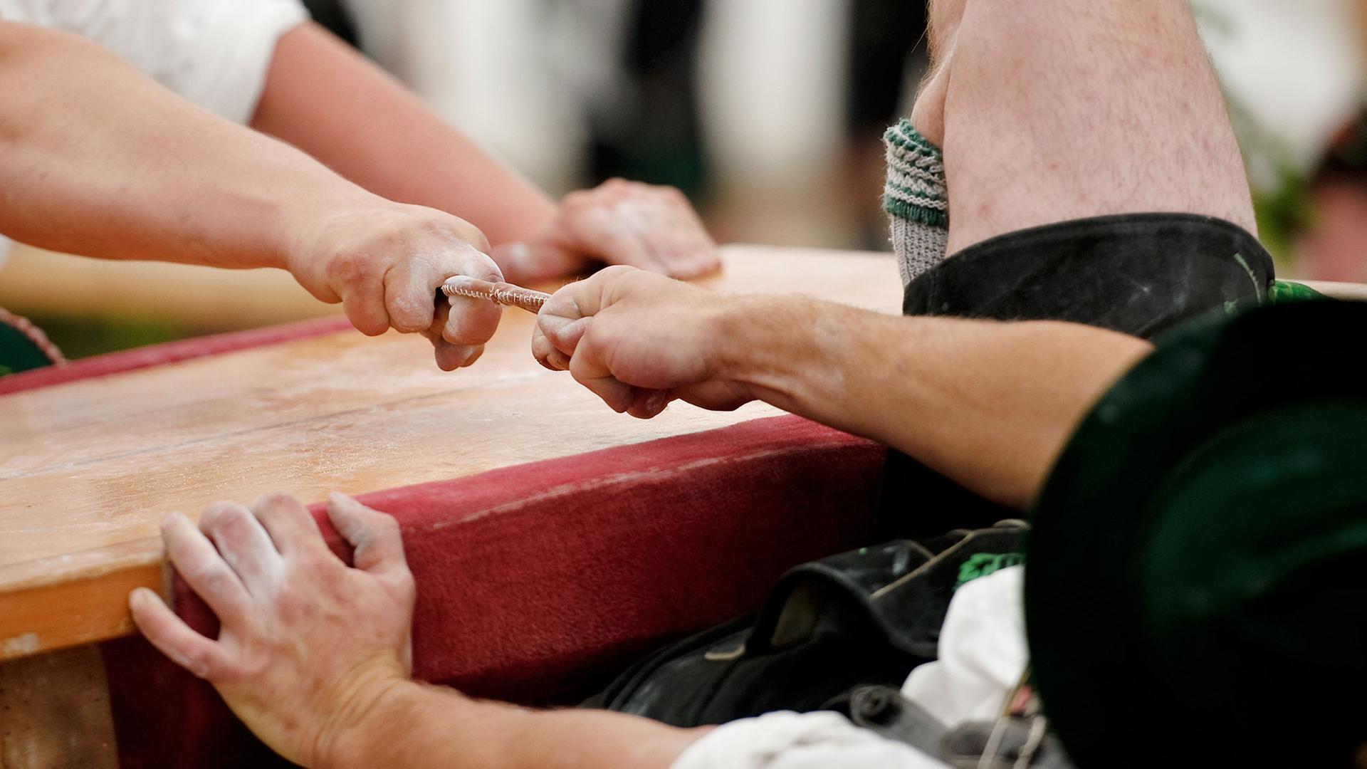 Teilnehmer kämpfen am in Garmisch-Partenkirchen (Oberbayern) um die Deutsche Meisterschaft im Fingerhakeln. Die Gegner sitzen sich bei dem Wettbewerb auf Hockern an einem Tisch gegenüber und versuchen, den Gegner am Finger zu sich herüberzuziehen. Hinter jedem Hakler sitzt ein Auffänger. Teilnehmer kämpfen am in Garmisch-Partenkirchen (Oberbayern) um die Deutsche Meisterschaft im Fingerhakeln. Die Gegner sitzen sich bei dem Wettbewerb auf Hockern an einem Tisch gegenüber und versuchen, den Gegner am Finger zu sich herüberzuziehen. Hinter jedem Hakler sitzt ein Auffänger.