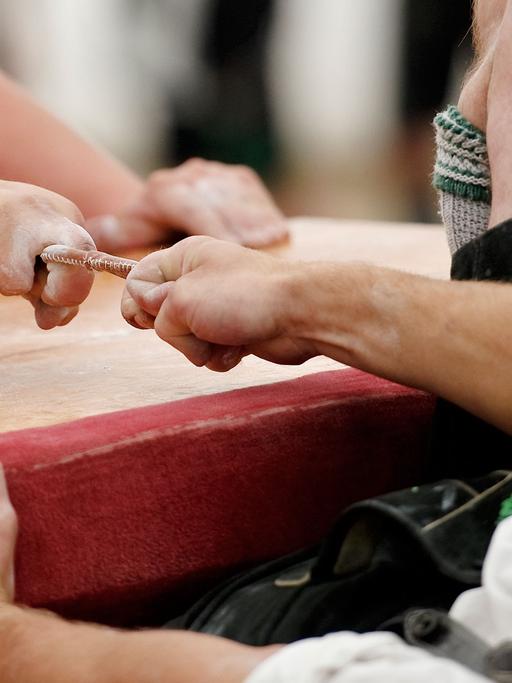 Teilnehmer kämpfen am in Garmisch-Partenkirchen (Oberbayern) um die Deutsche Meisterschaft im Fingerhakeln. Die Gegner sitzen sich bei dem Wettbewerb auf Hockern an einem Tisch gegenüber und versuchen, den Gegner am Finger zu sich herüberzuziehen. Hinter jedem Hakler sitzt ein Auffänger.