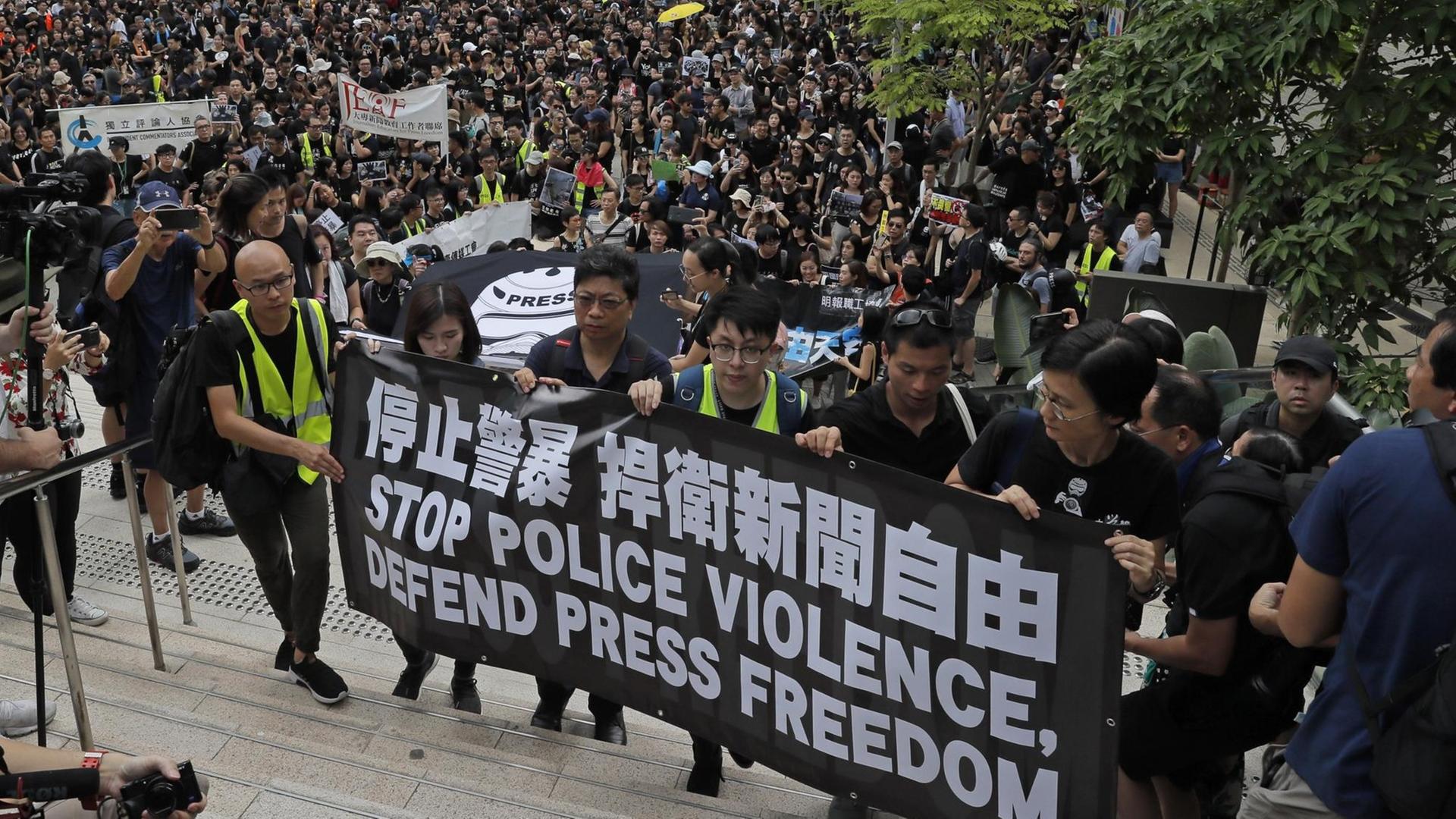 Journalisten in Hongkong halten bei einem Schweigemarsch ein Banner mit der Aufschrift "Stoppt Polizeigewalt, verteidigt Pressefreiheit" hoch. Journalisten in Hongkong halten bei einem Schweigemarsch ein Banner mit der Aufschrift "Stoppt Polizeigewalt, verteidigt Pressefreiheit" hoch.