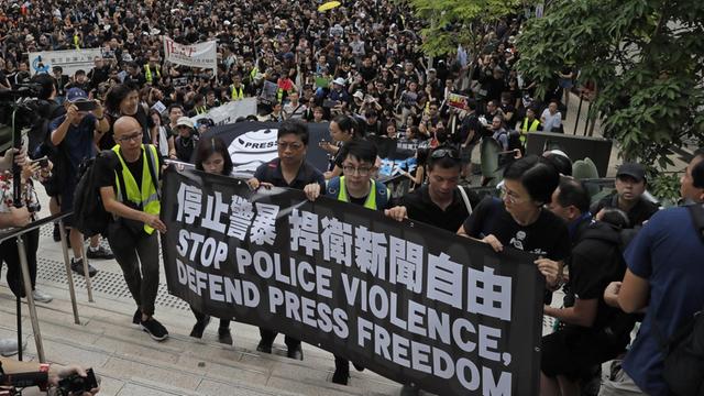 Journalisten in Hongkong halten bei einem Schweigemarsch ein Banner mit der Aufschrift "Stoppt Polizeigewalt, verteidigt Pressefreiheit" hoch.