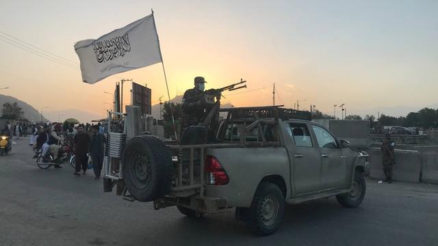 Taliban, bewaffnet, stehen auf einem Pick-up.