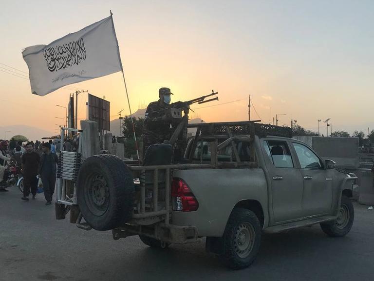 Taliban, bewaffnet, stehen auf einem Pick-up.