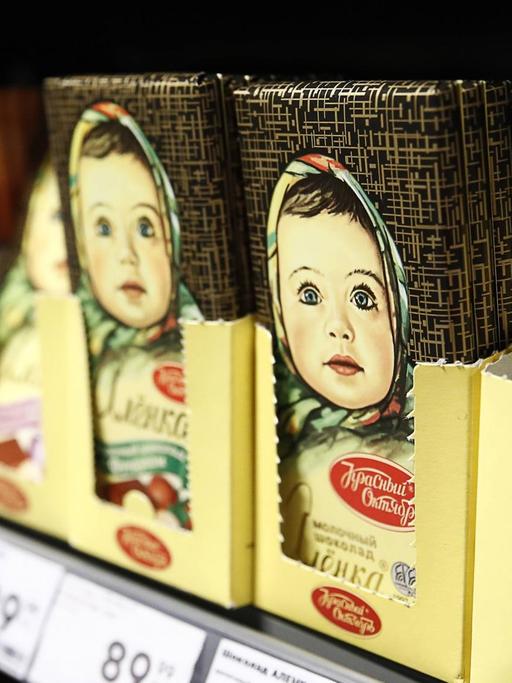 In einem Supermarktregal sind Schokoladentafeln aufgereiht. Darauf zu sehen ist ein Mädchen mit bäuerlichem Kopftuch.