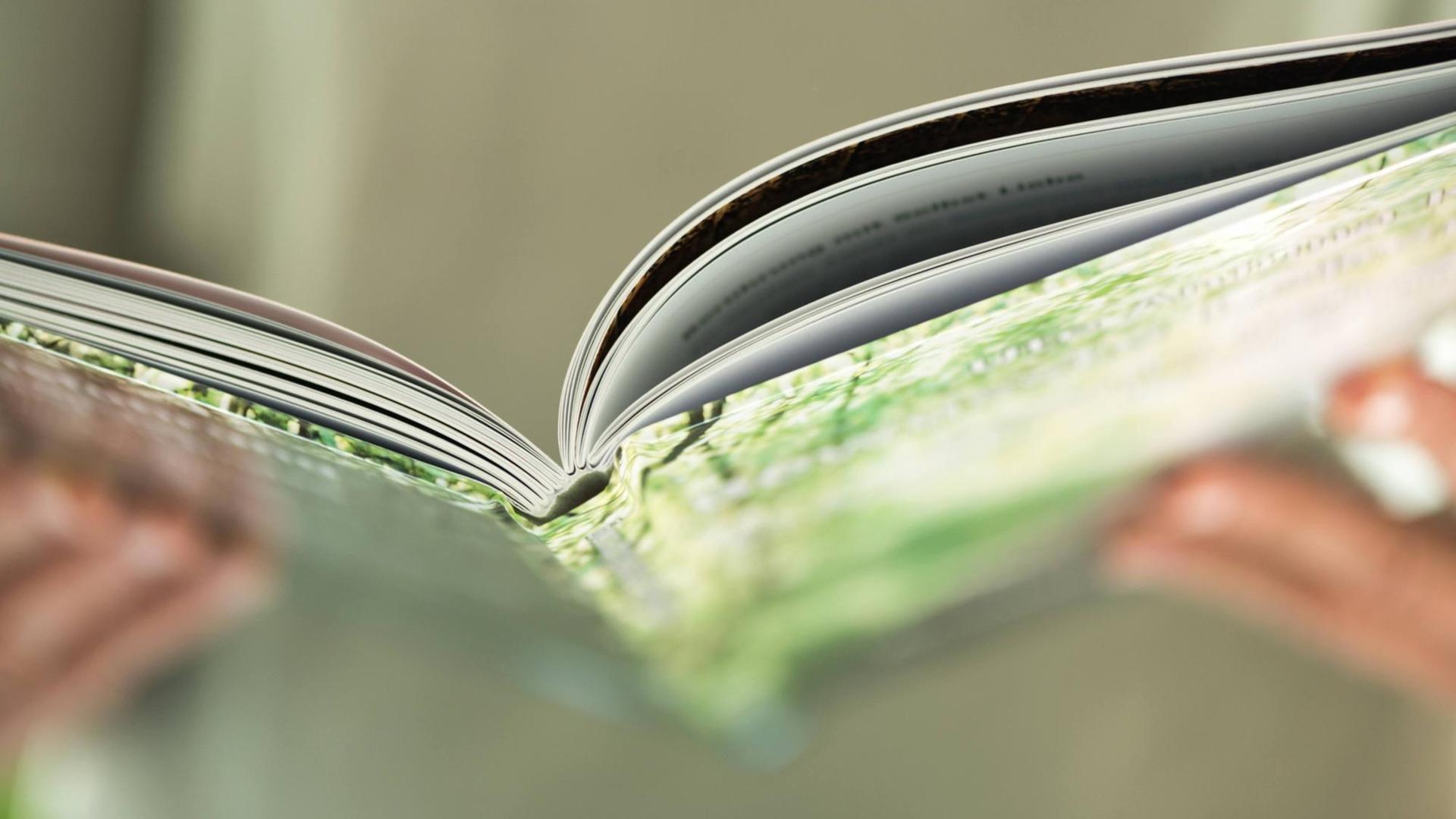 Aufgeschlagenes Hardcover-Buch mit Händen Aufgeschlagenes Hardcover-Buch mit Händen