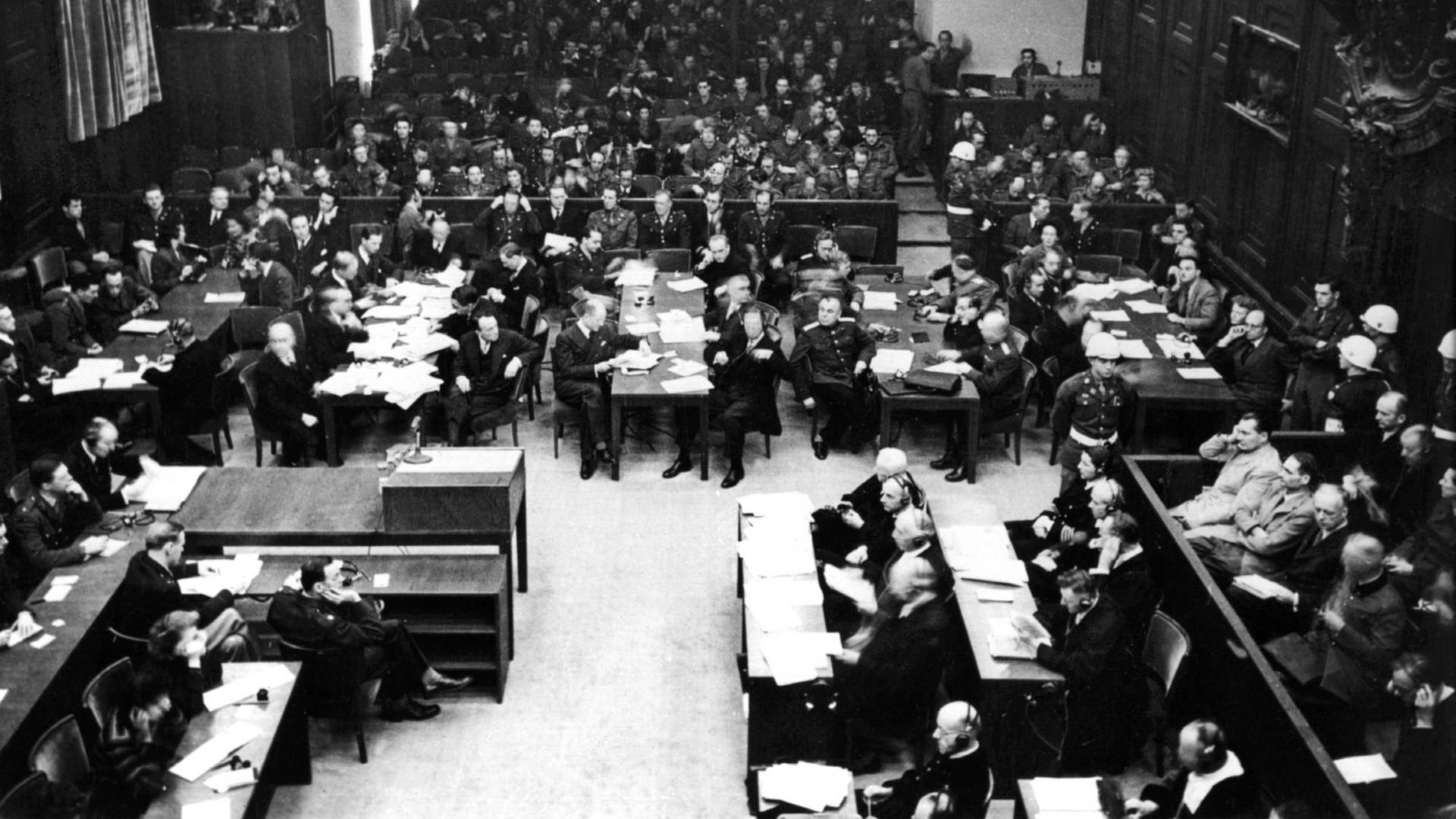 Blick in den Nürnberger Justizpalast während der Eröffnung des Hauptkriegsverbrecherprozesses am 20. November 1945 vor dem Internationalen Militärgerichtshof. Rechts die Angeklagten, vor ihnen die Verteidiger, im Hintergund die Staatsanwälte, ganz hinten die Pressevertreter. Oben auf der Galerie Zuschauer. Blick in den Nürnberger Justizpalast während der Eröffnung des Hauptkriegsverbrecherprozesses am 20. November 1945 vor dem Internationalen Militärgerichtshof. Rechts die Angeklagten, vor ihnen die Verteidiger, im Hintergund die Staatsanwälte, ganz hinten die Pressevertreter. Oben auf der Galerie Zuschauer.