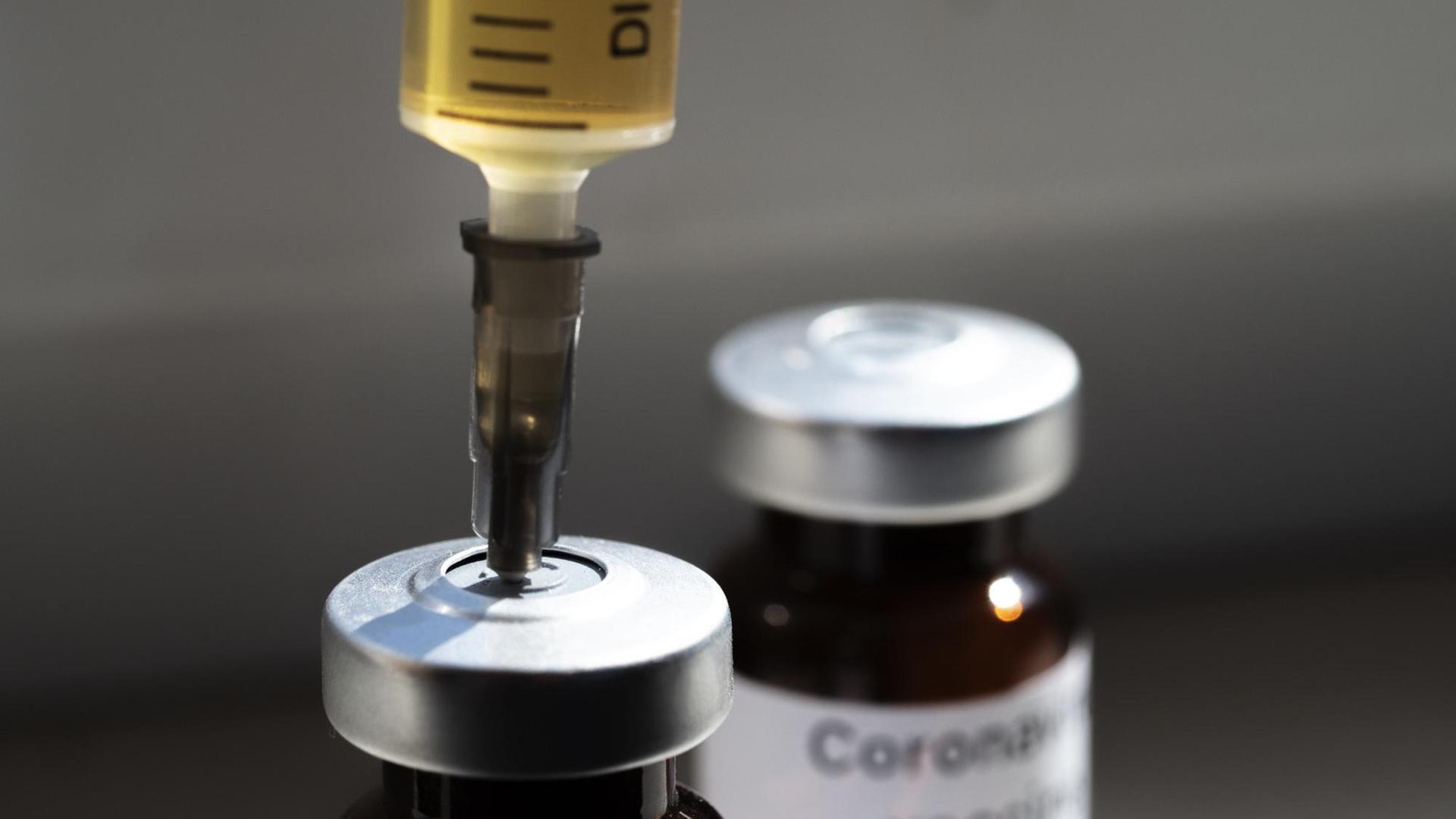 Eine Spritze steckt in einem Fläschchen mit der Aufschrift "Coronavirus-Impfstoff" und Eine Spritze steckt in einem Fläschchen mit der Aufschrift "Coronavirus-Impfstoff" und