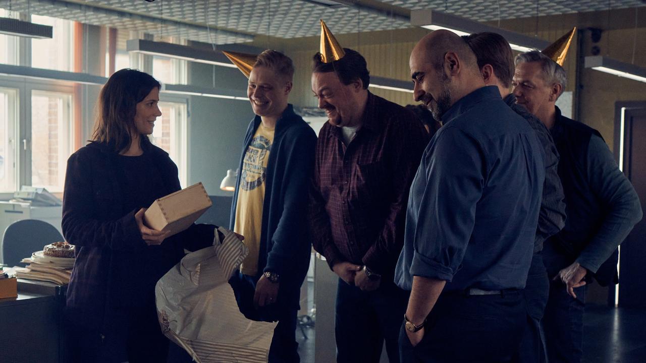 Szene aus der Serie "Unbroken". Auf dem Revier überreichen Küken (Karl Schaper), Rensmann (Sascha Nathan), Paul Nowak (Özgür Karadeniz) und die restlichen Kollegen Alex (Aylin Tezel) ein Geschenk, das sie auspackt. Szene aus der Serie "Unbroken". Auf dem Revier überreichen Küken (Karl Schaper), Rensmann (Sascha Nathan), Paul Nowak (Özgür Karadeniz) und die restlichen Kollegen Alex (Aylin Tezel) ein Geschenk, das sie auspackt.