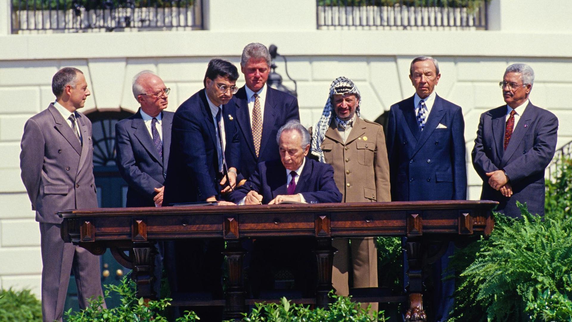 Shimon Peres setzt am 13. September 1993 in Washington seine Unterschrift unter das Abkommen von Oslo, hinter ihm stehen u.a. der israelische Premierminister Jitzhak Rabin, PLO-Chef Jassir Arafat und US-Präsident Bill Clinton. Shimon Peres setzt am 13. September 1993 in Washington seine Unterschrift unter das Abkommen von Oslo, hinter ihm stehen u.a. der israelische Premierminister Jitzhak Rabin, PLO-Chef Jassir Arafat und US-Präsident Bill Clinton.
