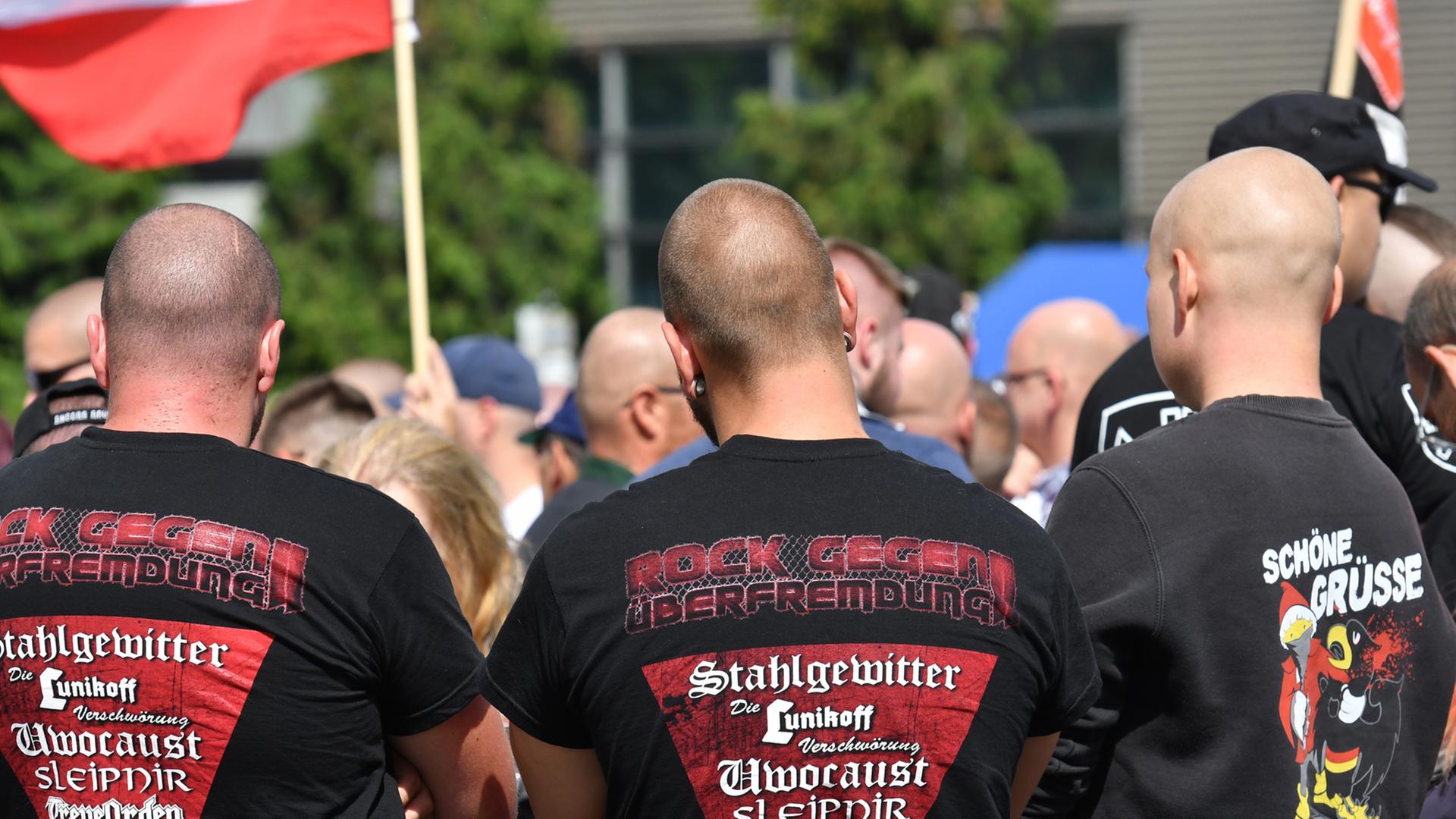 Drei Männer stehen mit dem Rücken zur Kamera, sie haben Glatzen auf dem T-Shirts des Mannes in der Mitte steht: "Rock gegen Überfremdung" Drei Männer stehen mit dem Rücken zur Kamera, sie haben Glatzen auf dem T-Shirts des Mannes in der Mitte steht: "Rock gegen Überfremdung"