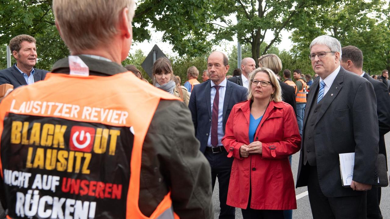 Svenja Schulze, Ministerin für Umwelt, Naturschutz und nukleare Sicherheit, und Brandenburgs Wirtschaftsminister Jörg Steinbach (rechts, beide SPD) werden vor dem Braunkohle-Kraftwerk "Schwarze Pumpe" von Helmar Rendez (links), Vorstandsvorsitzender der Lausitz Energie Bergbau AG (LEAG), und von Demonstranten in orangenen Westen mit der Aufschrift "Black out Lausitz Nicht auf unseren Rücken" empfangen. Svenja Schulze, Ministerin für Umwelt, Naturschutz und nukleare Sicherheit, und Brandenburgs Wirtschaftsminister Jörg Steinbach (rechts, beide SPD) werden vor dem Braunkohle-Kraftwerk "Schwarze Pumpe" von Helmar Rendez (links), Vorstandsvorsitzender der Lausitz Energie Bergbau AG (LEAG), und von Demonstranten in orangenen Westen mit der Aufschrift "Black out Lausitz Nicht auf unseren Rücken" empfangen.