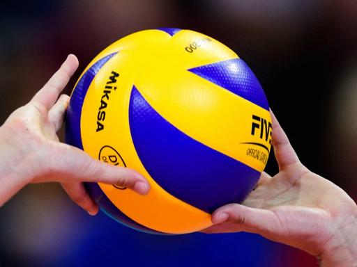 Großaufnahme: Zwei Hände pritschen einen Volleyball