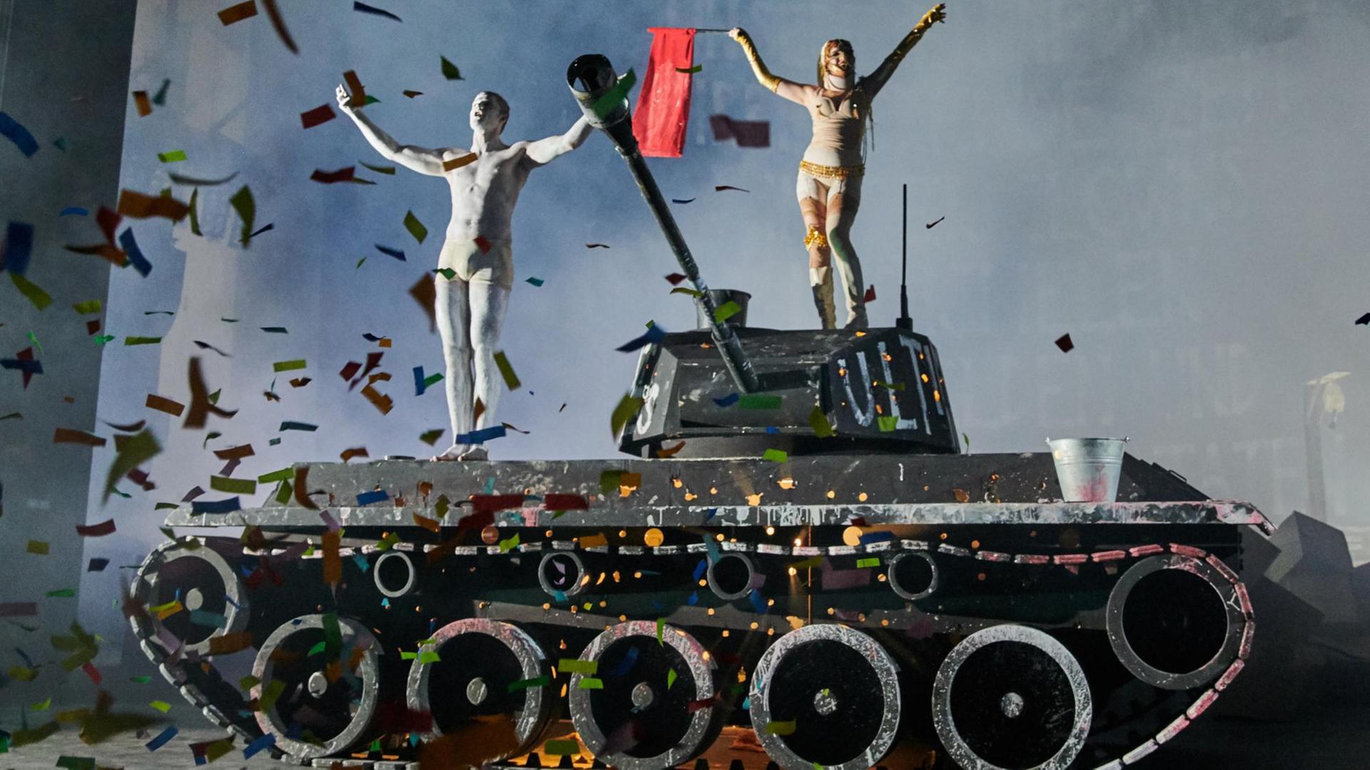 Die Schauspieler Theo Trebs und Jella Haase tanzen auf einem Panzer im Stück "Eine Odyssee“ an der Berliner Volksbühne