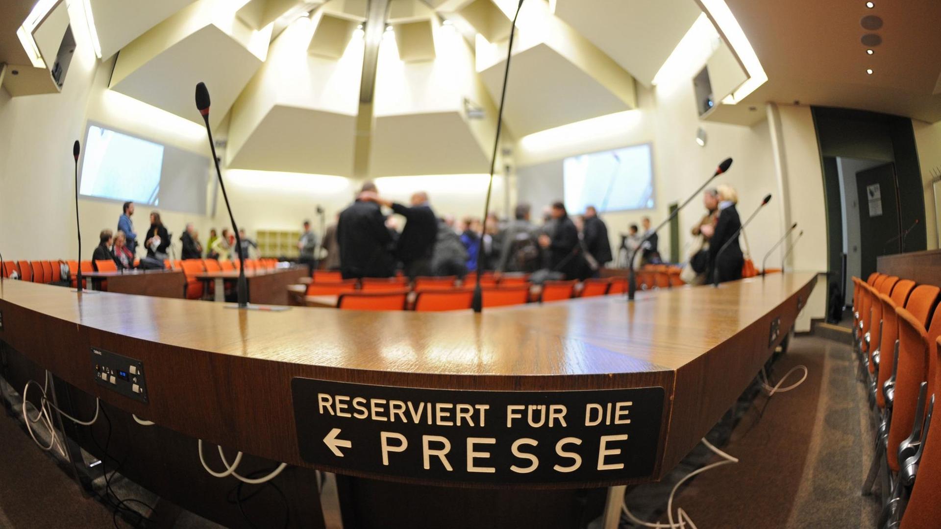 Ein Schild markiert die Sitzplätze im Gerichtssaal für Journalisten. Im Hintergrund ist verschwommen der Raum zu sehen. Ein Schild markiert die Sitzplätze im Gerichtssaal für Journalisten. Im Hintergrund ist verschwommen der Raum zu sehen.