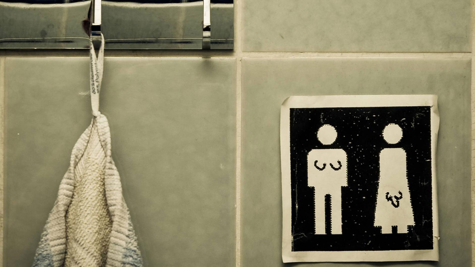 Unisex Handtuch. Symbole auf einem Schild: Für Männer und Frauen. Jemand hat signifikante Körpermerkmale für Transgender People ergänzt. Unisex Handtuch. Symbole auf einem Schild: Für Männer und Frauen. Jemand hat signifikante Körpermerkmale für Transgender People ergänzt.