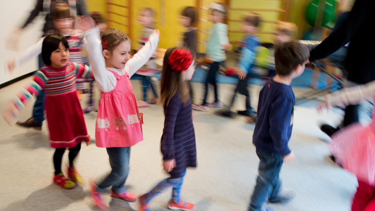 Kinder tanzen während einer Musikstunde durch eine Kindertagesstätte.