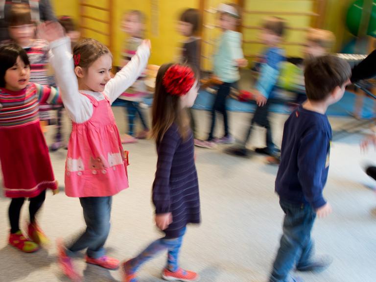 Kinder tanzen während einer Musikstunde durch eine Kindertagesstätte.