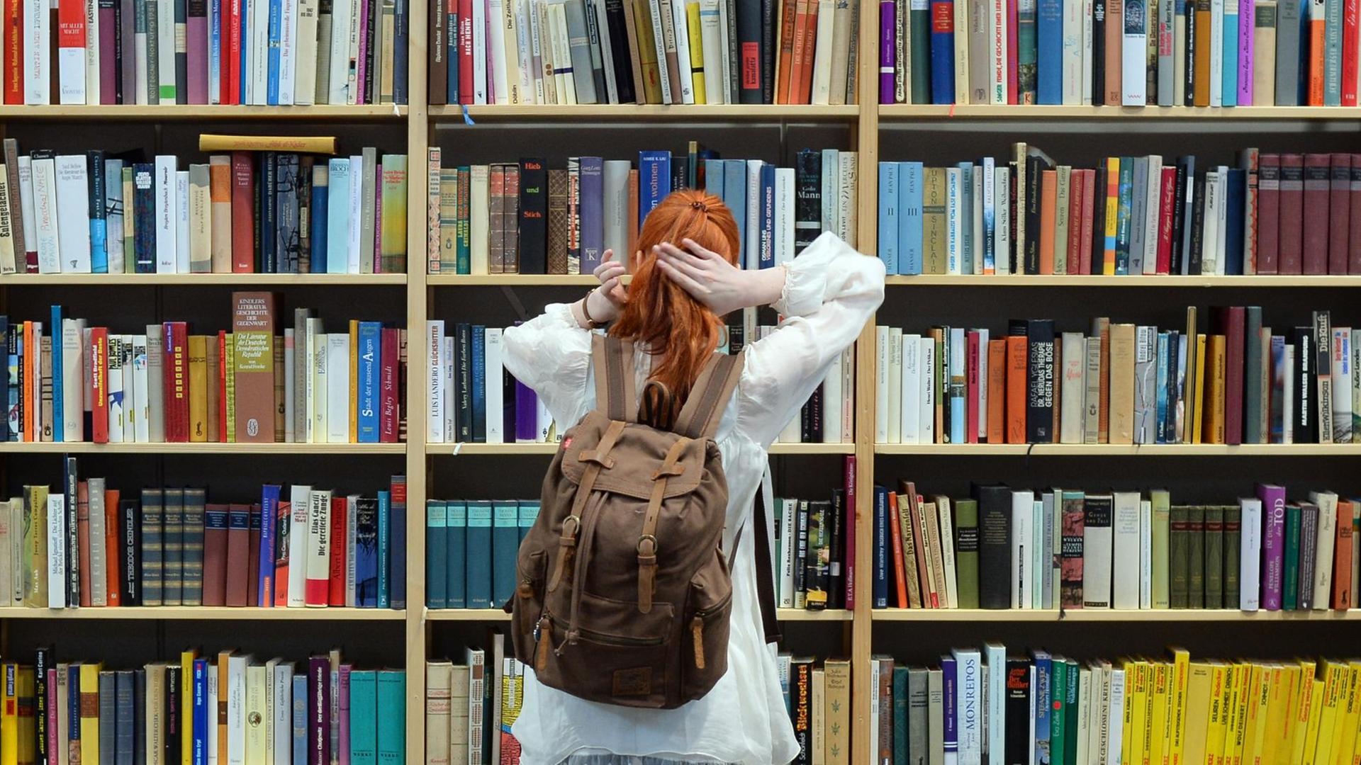 Eine Besucherin steht am 26.03.2017 auf der Buchmesse Leipzig (Sachsen) an einem Regal mit Büchern. Eine Besucherin steht am 26.03.2017 auf der Buchmesse Leipzig (Sachsen) an einem Regal mit Büchern.