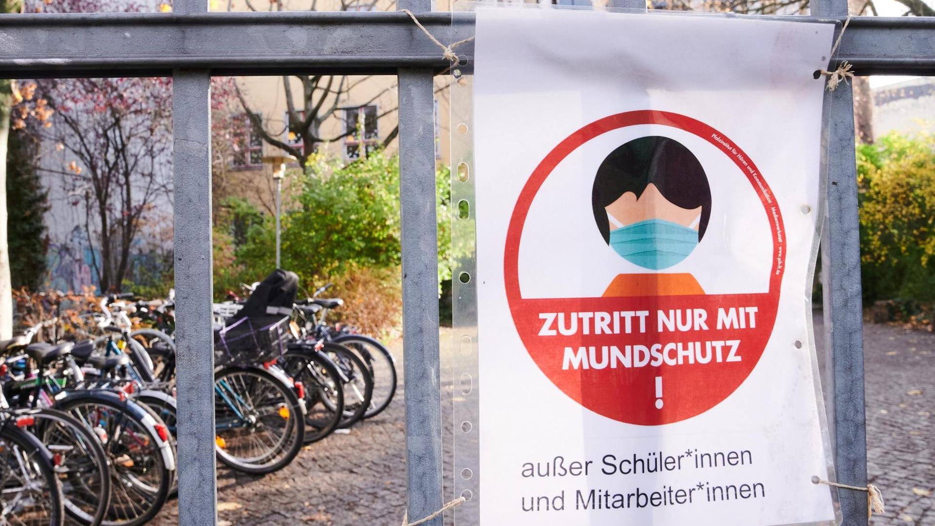 "Zutritt nur mit Mundschutz!" steht auf einem Schild am Eingang zu einer Schule.