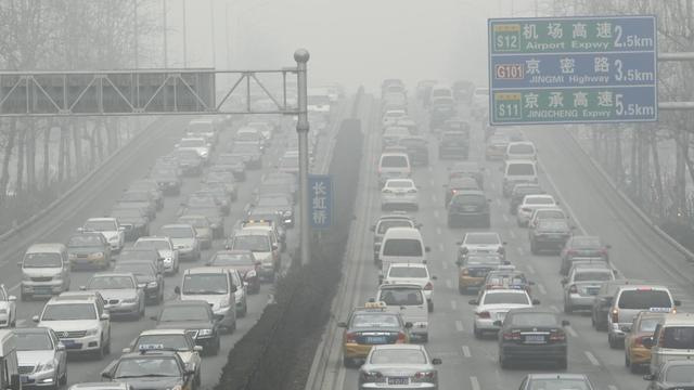 Im dichten Pekinger Stadtverkehr fahren die Autos durch den Smog.