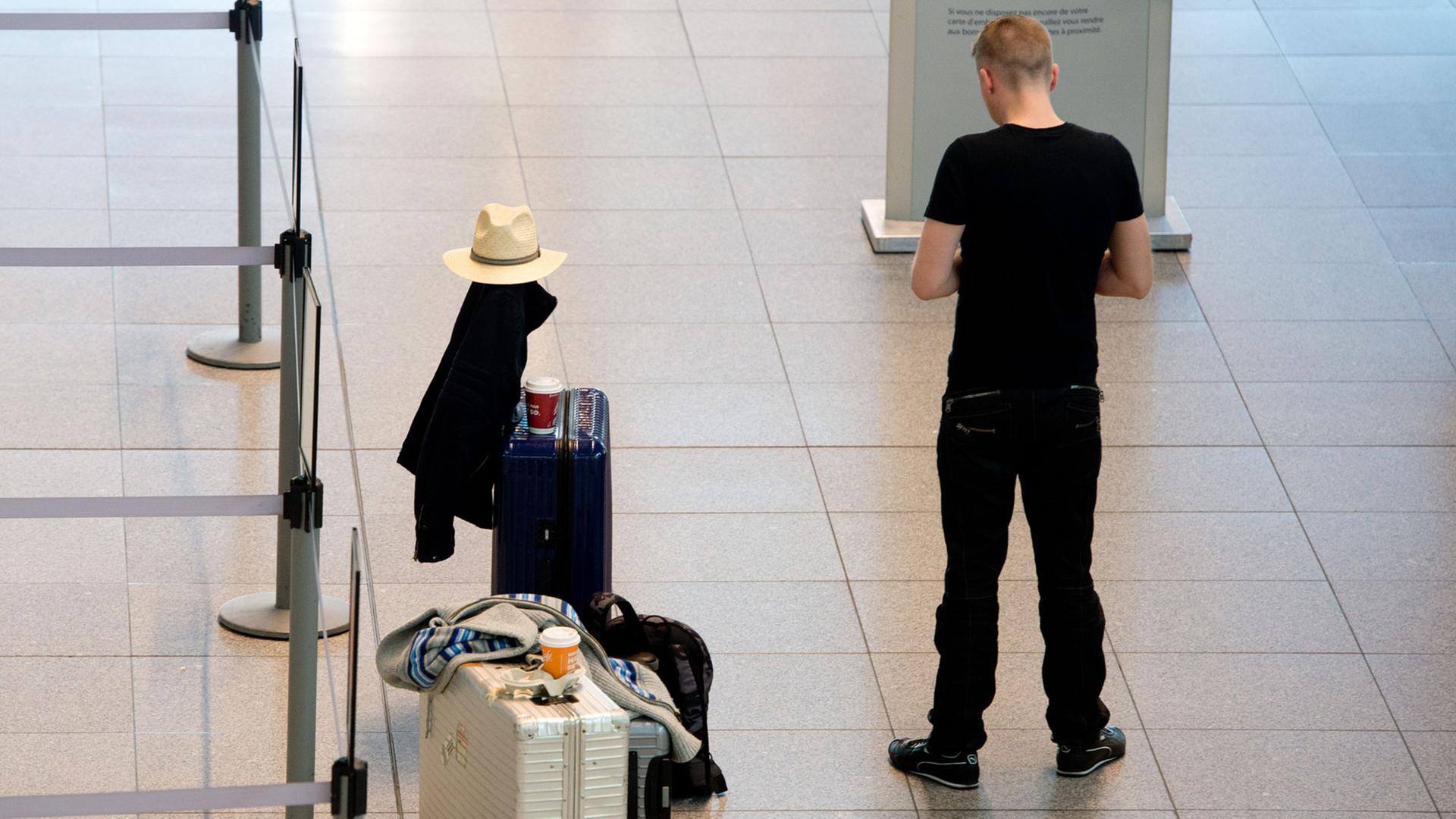 Ein Mann steht am 27.03.2014 während eines Warnstreiks auf dem Flughafen in Stuttgart (Baden-Württemberg) neben seinem Gepäck. Ein Mann steht am 27.03.2014 während eines Warnstreiks auf dem Flughafen in Stuttgart (Baden-Württemberg) neben seinem Gepäck.