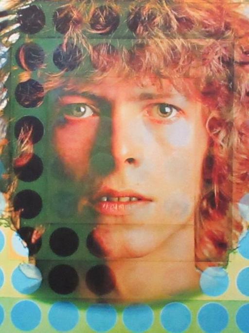 Zu sehen ist ein Ausschnitt des Plattencovers des Albums «Space Oddity». Es wurde vom Künstler Victor Vasarely im quadratischem Format gestaltet und besteht aus Punkten in unterschiedlichen Blautönen. In der Bildmitte das prägnante Gesicht von David Bowie mit lockigem, rötlichem Haar.