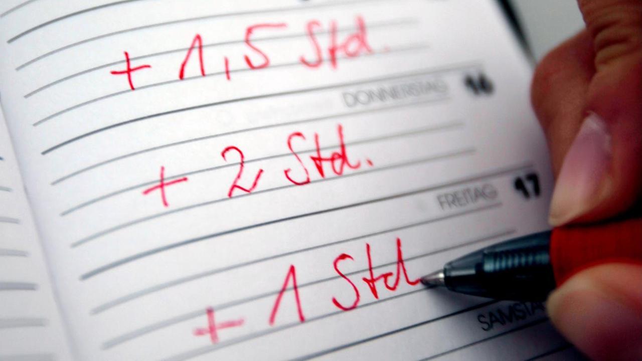 Jemand trägt seine Überstunden mit rotem Stift in einen Taschenkalender ein. Jemand trägt seine Überstunden mit rotem Stift in einen Taschenkalender ein.