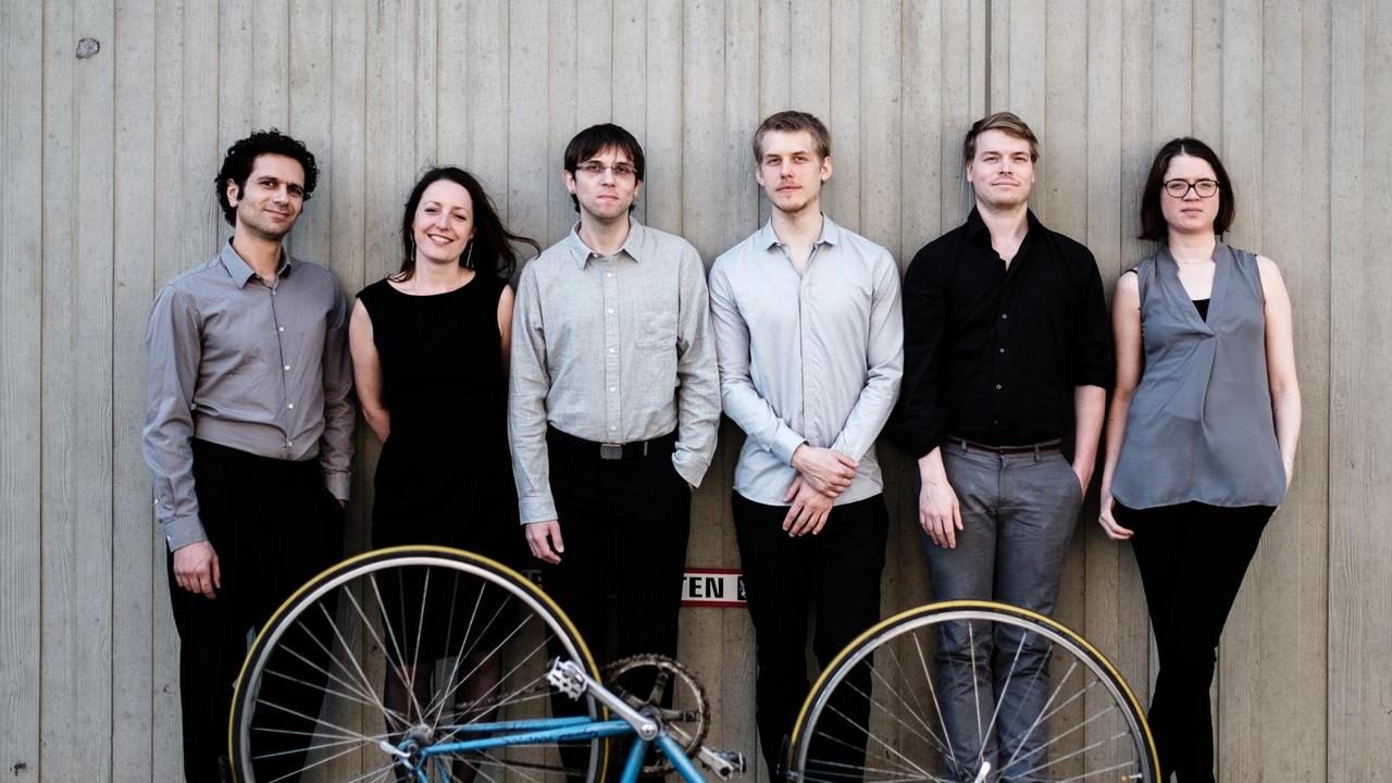 Das Ensemble hand werk in der Reihe stehend hinter einem umgedrehten Fahrrad Das Ensemble hand werk in der Reihe stehend hinter einem umgedrehten Fahrrad