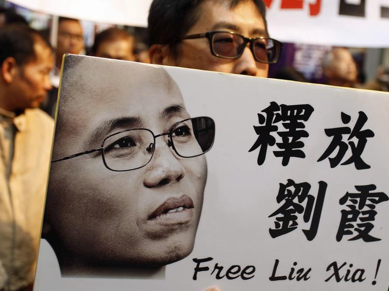  Ein Demonstrant in Hong Kong hält ein Plakat mit einem Bild von Liu Xia, hoch, darauf steht: Free Liu Xia - auf Englisch und Chinesisch.