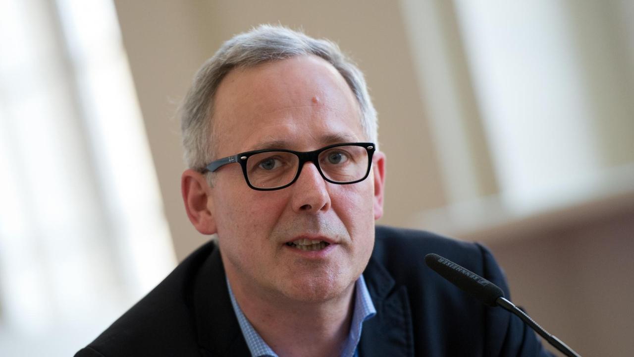 Ein Mann mit schwarzer Brille und grauem Haar schaut in die Kamera. Ein Mann mit schwarzer Brille und grauem Haar schaut in die Kamera.