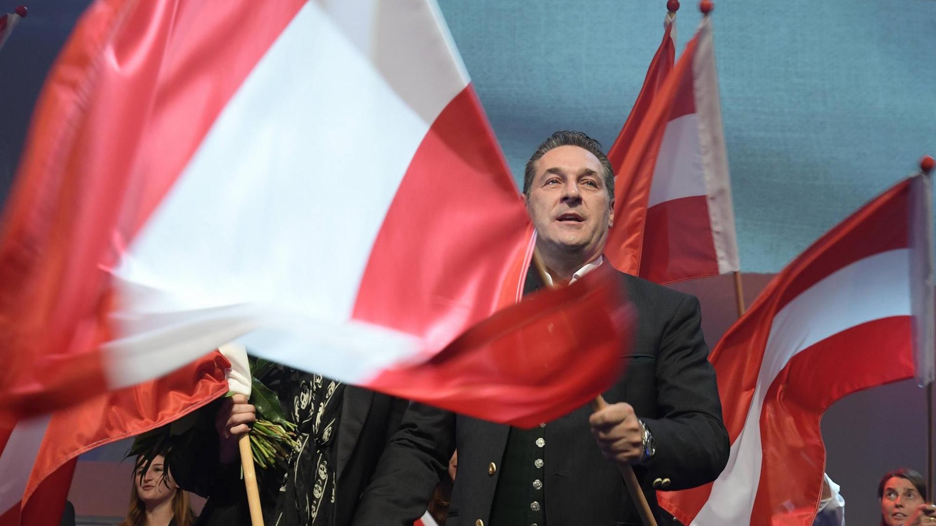 Heinz-Christian Strache schwenkt eine große österreichische Fahne auf einer Bühne. Heinz-Christian Strache schwenkt eine große österreichische Fahne auf einer Bühne.