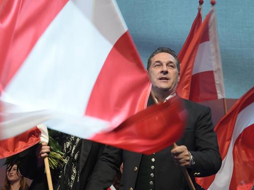 Heinz-Christian Strache schwenkt eine große österreichische Fahne auf einer Bühne.