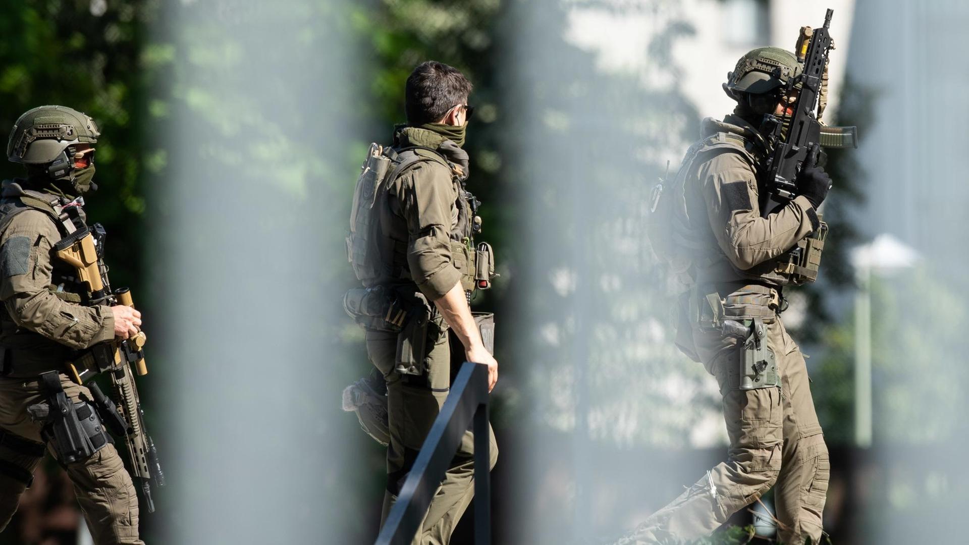 Durch einen unscharfen Zaun hindurch sind bewaffnete Polizisten zu sehen. Durch einen unscharfen Zaun hindurch sind bewaffnete Polizisten zu sehen.