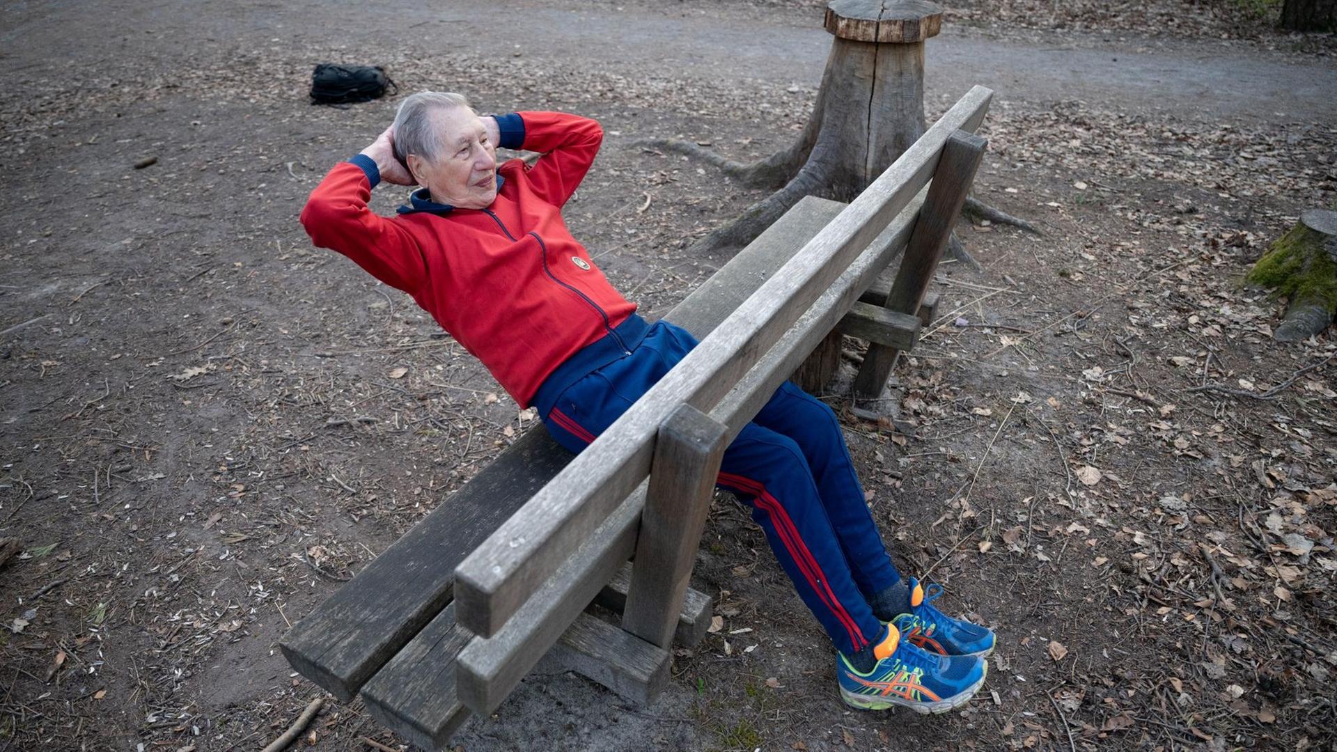 Ein alter Mann macht Sit-ups auf einer Bank. Ein alter Mann macht Sit-ups auf einer Bank.