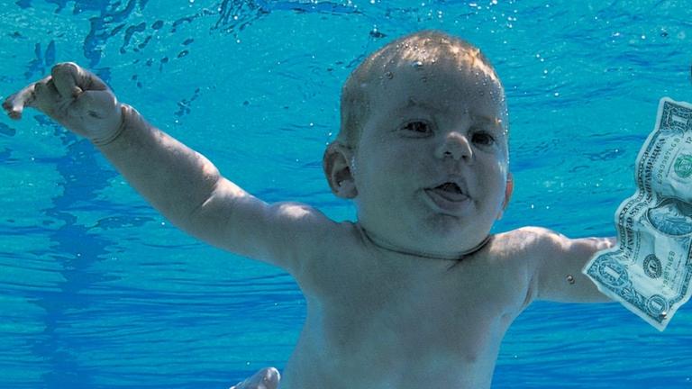 Ein Baby schwimmt in einem Pool einer Dollarnote hinterher. Ein Baby schwimmt in einem Pool einer Dollarnote hinterher.