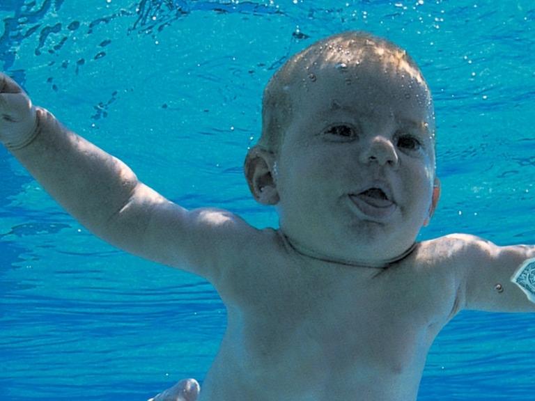 Ein Baby schwimmt in einem Pool einer Dollarnote hinterher.