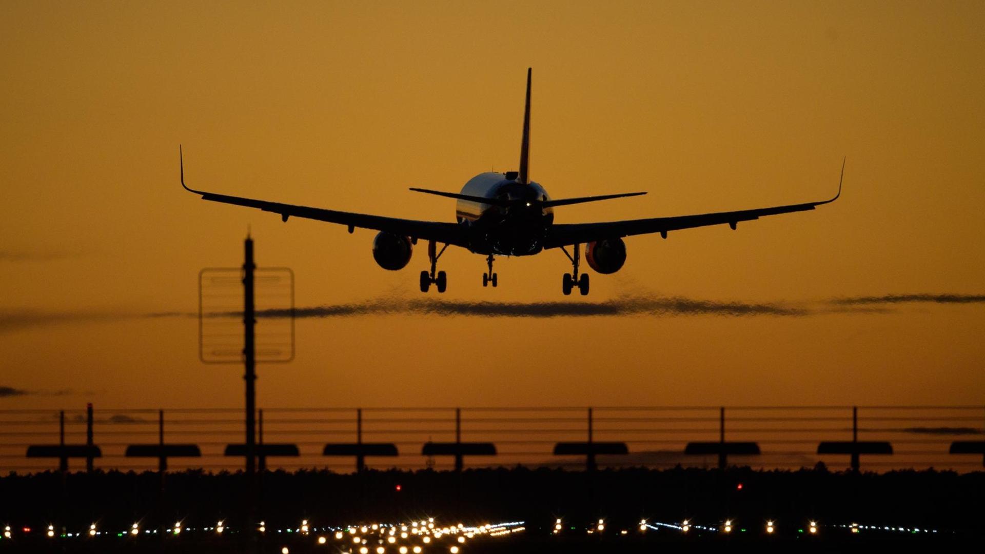 Ein Flugzeug landet auf dem Flughafen Berlin Brandenburg (BER) vor rotem Abendhimmel. Ein Flugzeug landet auf dem Flughafen Berlin Brandenburg (BER) vor rotem Abendhimmel.