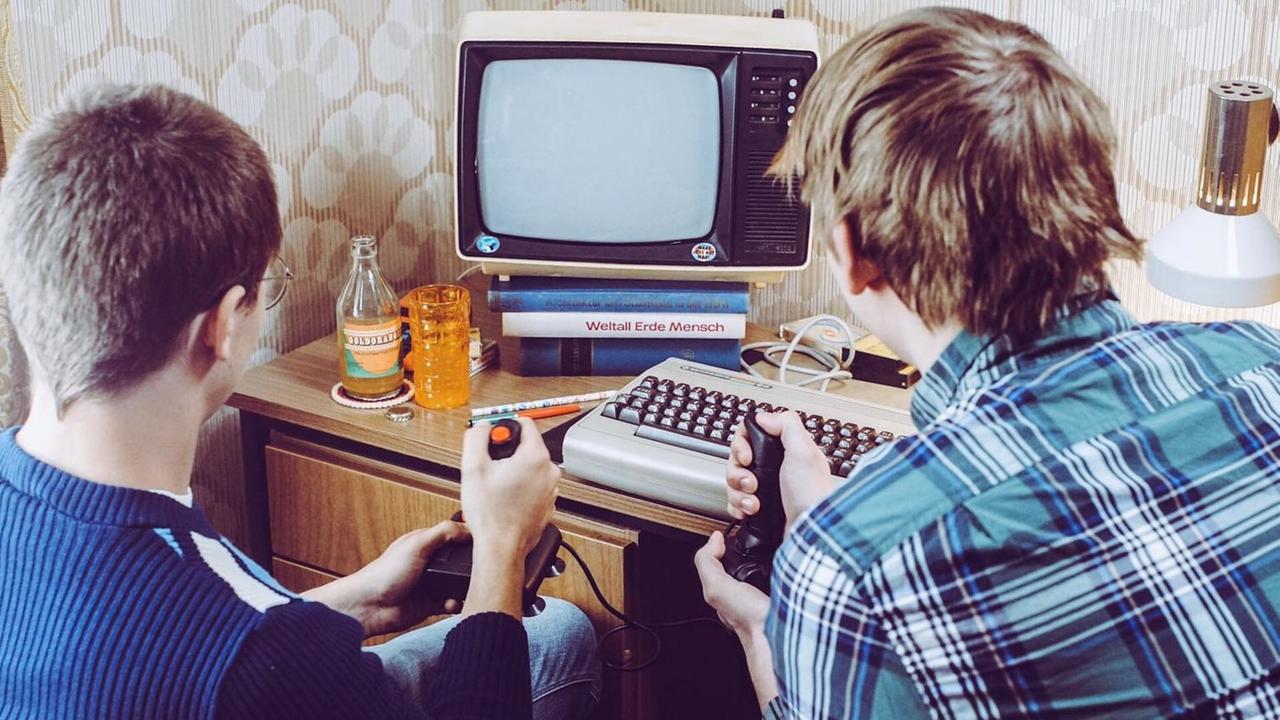 Zwei Jugendliche spielen mit Joysticks an einem Heimcomputer der 80er Jahre, mit Joystick, C64 und russischem Schwarzweißfernseher (nachgestellte Filmszene) Zwei Jugendliche spielen mit Joysticks an einem Heimcomputer der 80er Jahre, mit Joystick, C64 und russischem Schwarzweißfernseher (nachgestellte Filmszene)