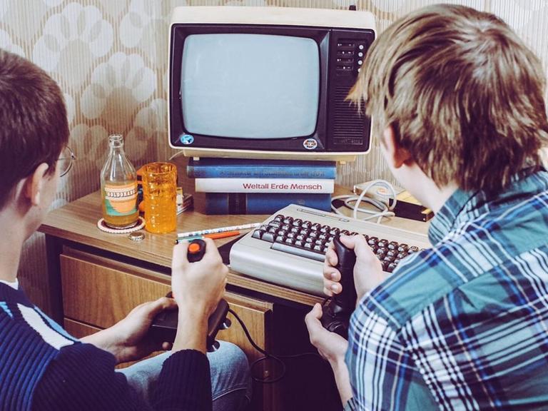 Zwei Jugendliche spielen mit Joysticks an einem Heimcomputer der 80er Jahre, mit Joystick, C64 und russischem Schwarzweißfernseher (nachgestellte Filmszene)